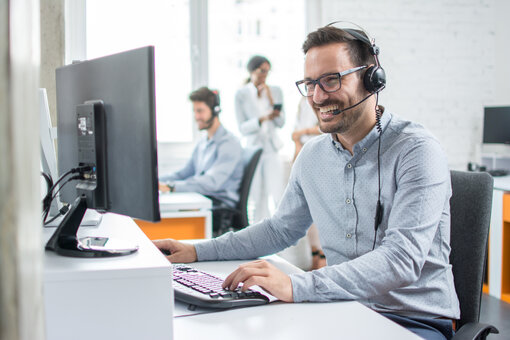 AdobeStock_194120492_GuyInCall Guy in call, on pc, smiling, phone call, meeting, office,