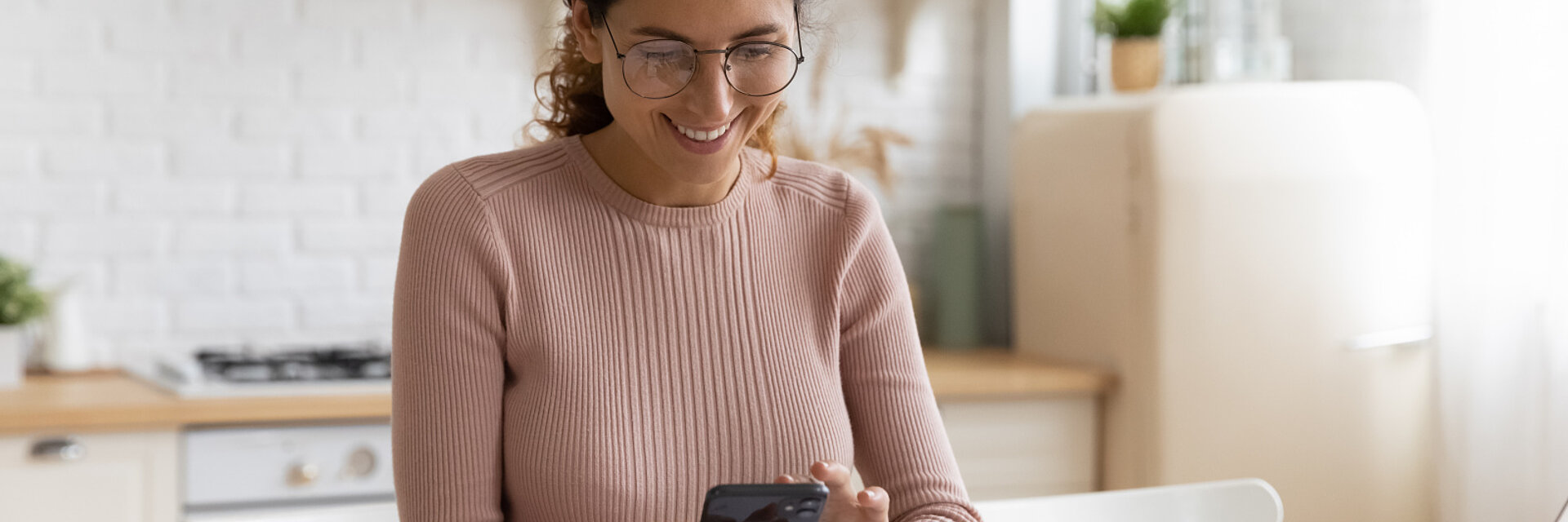 Smiling young Caucasian woman manage household budget finances paying bills taxes on smartphone online. Happy female busy with documents calculate expenses expenditures on cellphone on internet.